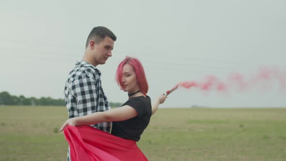 Positive Couple with Color Smoke Bomb Posing in Nature