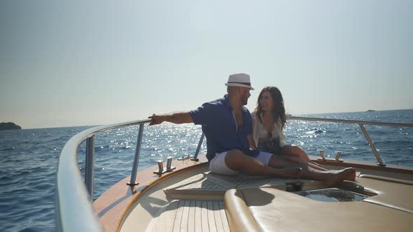 Happy couple sitting on sun deck of boat, talking