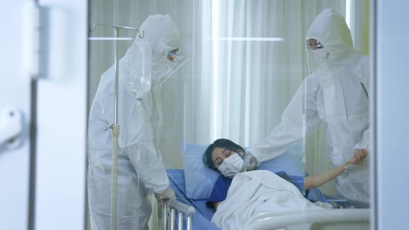 Covid19 Doctors in Ppe Suit with Face Mask Treating Young Woman Patient on Bed From Coronavirus