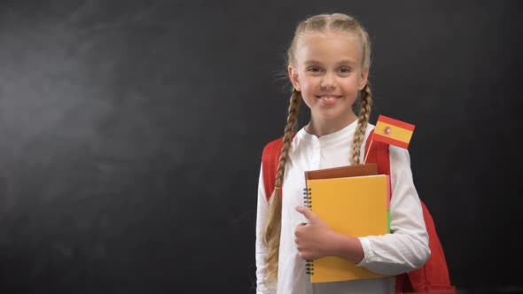 Joyful Pupil Holding Books With Tiny Spain Flag