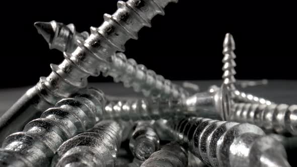 Pile of Steel Chrome Screws Rotating on Isolated Black Background