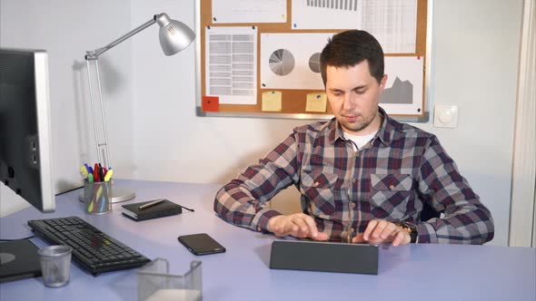 Office Worker Checks Incoming Mail on the Tablet Sitting in His Office.