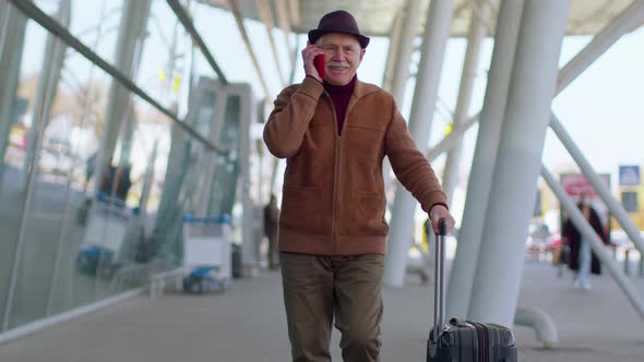 Senior Tourist Grandfather Man Walking on International Airport Hall Using Mobile Phone Talking