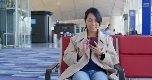 Businesswoman check on the cellphone and wait for the flight in the airport