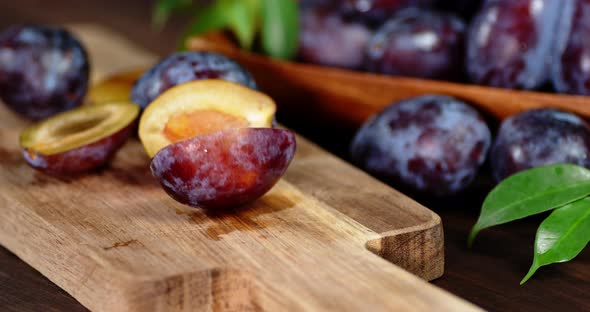 Half of Ripe Plums Swinging on a Cutting Board.