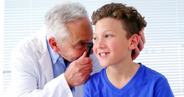 Male doctor examining a patients ear with horoscope