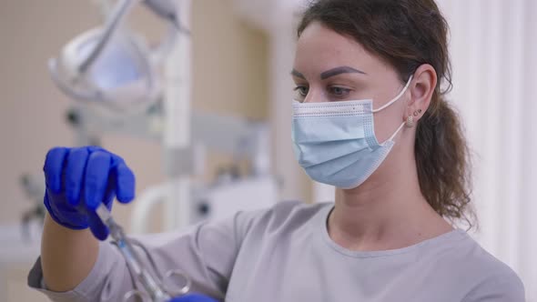 Concentrated Expert Caucasian Woman in Face Mask Opening Carpool Syringe Standing in Dentist Office