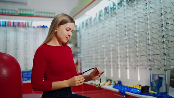 Woman examining eyeglasses. Happy woman choosing glasses at optical store