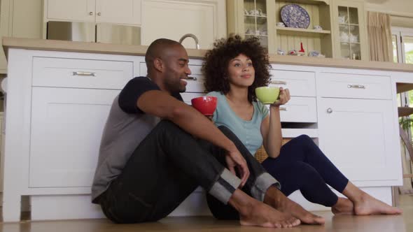 Happy mixed race couple drinking coffee in their kitchen