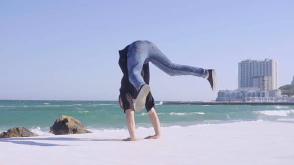 Young Strong Man Showing Impressive Strength Doing a Handstand on the Beach