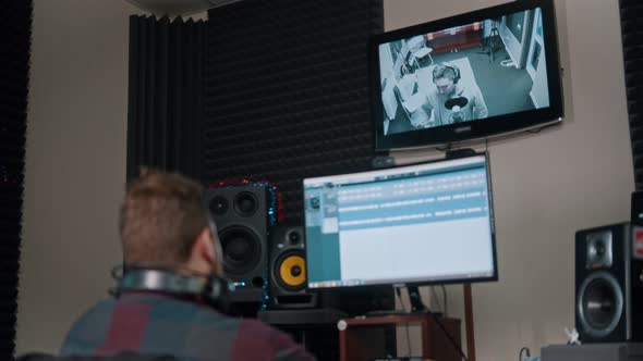 A Man Sound Engineer Recording Audio Tracks for a Young Man Rapper