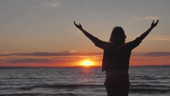 Silhouette of Strong Confidence Woman Open Arms Under the Sunset at Seacoast. Unity with Nature