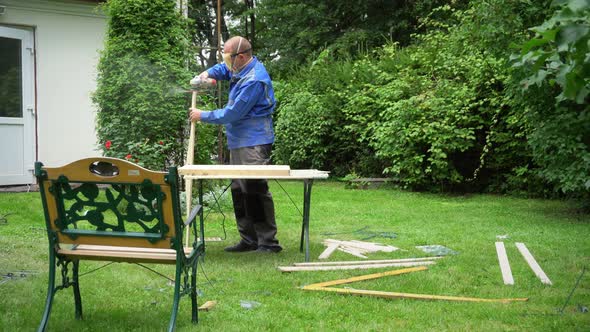 Male Worker Renewing Old Outdoor Furniture Bench