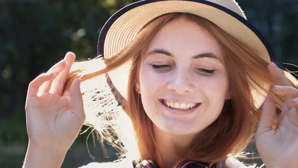 Portrait of pretty positive teenage girl with red hair wearing straw hat and pink 