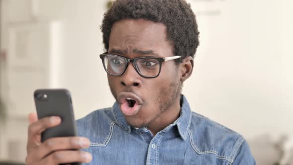 Excited Successful African Man Using Smartphone