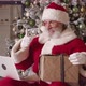 Cheerful Santa Claus Sitting on an Armchair Against a Christmas Tree Background in His Residence - VideoHive Item for Sale