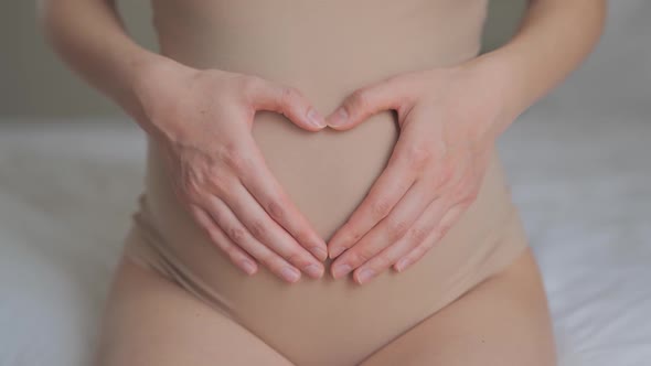 Future Mother Petting Abdomen and Showing Heart Shape