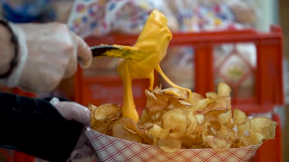 Extreme closeup in slow motion of putting cheese sauce on a serving of tornado or curly potato fries