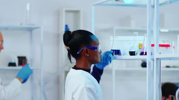 African Woman Chemist Researcher Using Glass Equipment in Lab