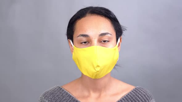 Attractive Young Woman Putting Yellow Mask Against Gray Background