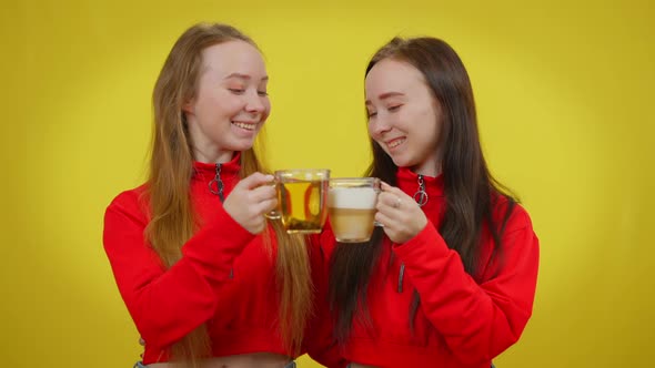 Slim Charming Twin Sisters Clinking Cups with Tea and Coffee Drinking Smiling Looking at Camera