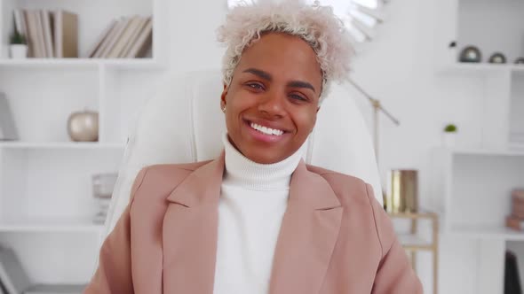 Successful African American Woman Smiling and Laughing While Sits in Chair