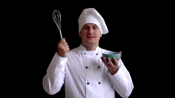 Chef of Caucasian Appearance Preparing To Work and Raises His Cup and Whisk for Cooking