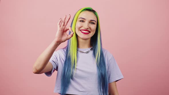 Young Carefree Woman with Rainbow Hairstyle Showing OK Gesture and Smiling to Camera Dancing Over