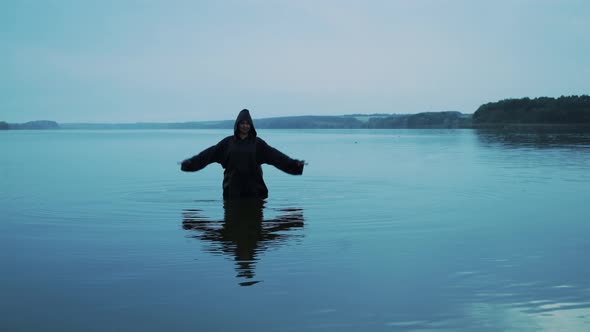 Female figure in black mantle in the river