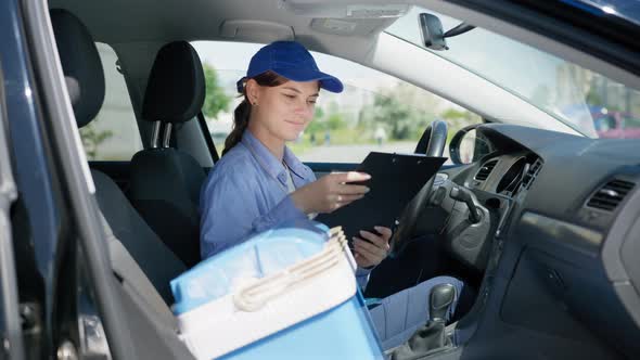 Young Attractive Woman Driver Working As Courier in Food Supply Service of Shop at Home Checks