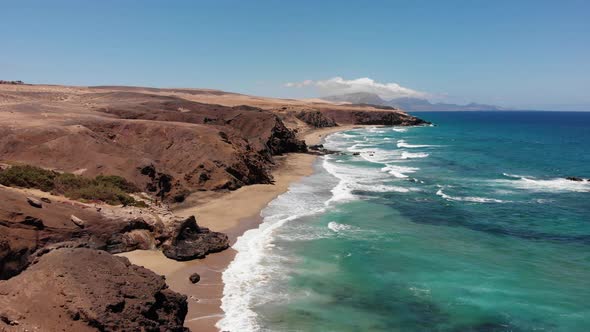 Aerial shot of the coast of La Pared beach in Fuerteventura on a sunny day. High cliffs and waves in