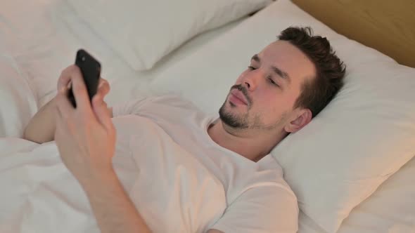 Young Man Get Shock on Smartphone in Bed