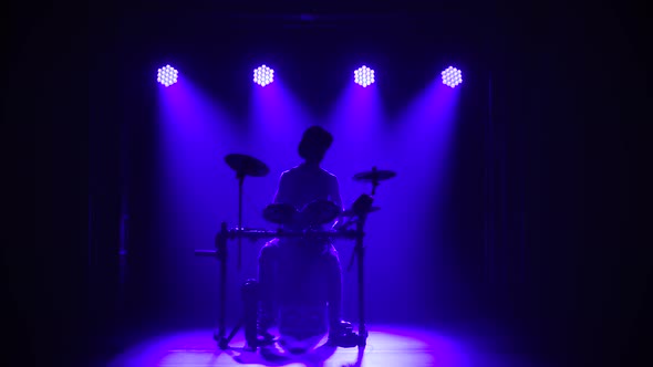 A Musician Drummer Who Plays a Musical Instrument in a Dark Studio, Silhouetted Against a Background