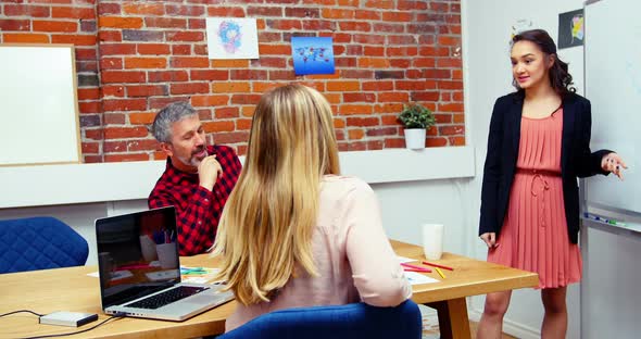 Business executives discussing over whiteboard during meeting