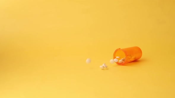 White Color Medical Pills Spilling on Yellow Background