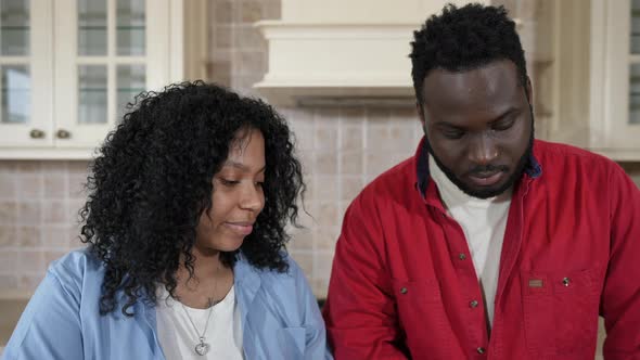 Front View Loving African American Wife Feeding Husband with Tomato in Kitchen at Home As Spouse