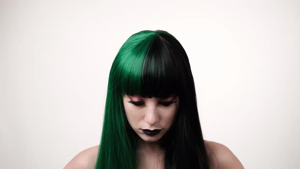 portrait of woman with a green black hair wig straightens long hair