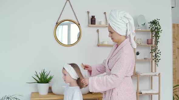 Woman Brushing Her Daughter Hair at Home