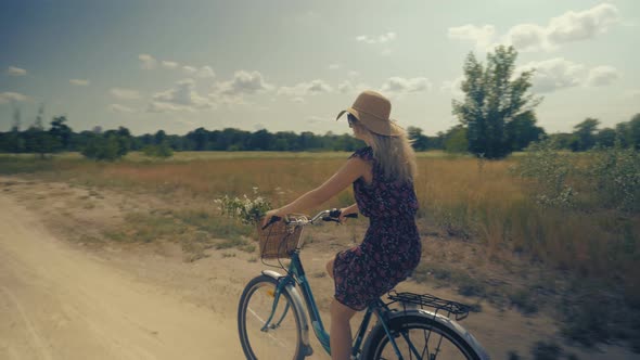 Cyclist Woman With Blonde Hair Cycling On Bike With Basket. Woman In Hat Riding On Bicycle At Summer