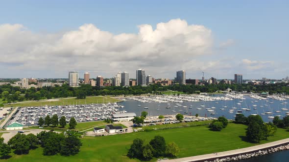 Wide pull away aerial view of sail boats in a quiet bay with city skyline in the background