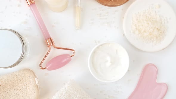 Rotation of Pink Quartz Facial Roller and Glass Bottle with Pipette with Gel Fluid Collagen Serum