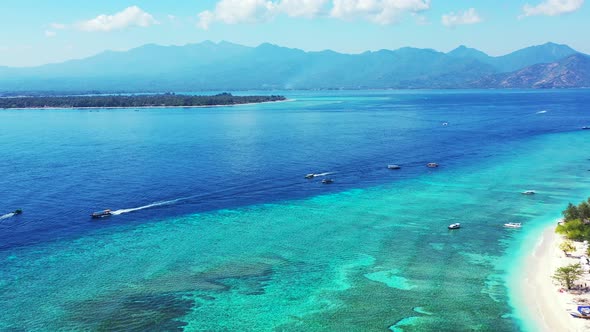 Boats sailing on blue sea stream around calm turquoise lagoon of tropical island full of coral reefs