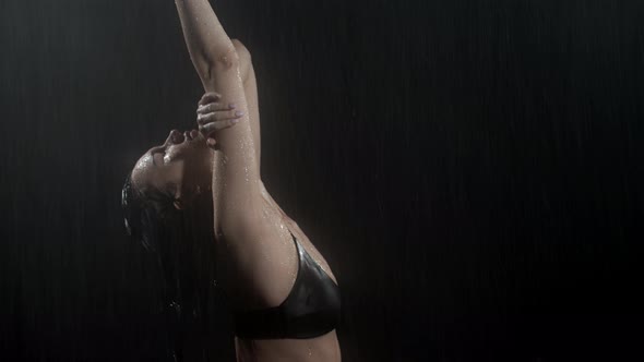 Young Woman in Black Bra Standing Under the Rain with Closed Eyes and Enjoying the Drops on Her Body