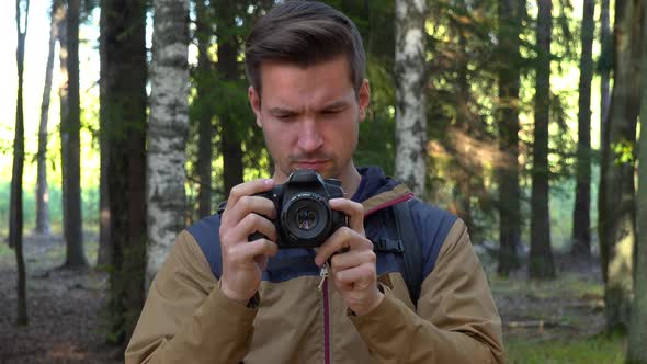 A Young Handsome Hiker Looks at the Pictures on His Camera - Closeup