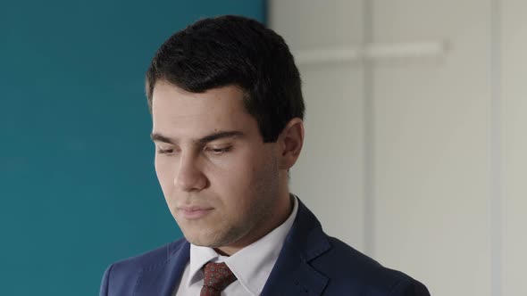 young pensive manager raising his head and staring at camera