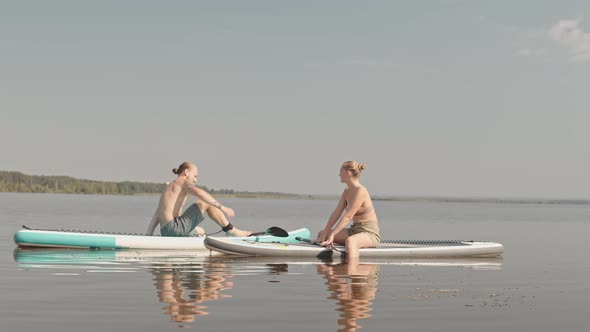 Couple Chatting on Sup Boards in Water