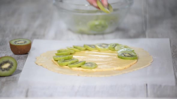 Female hands making galette with fresh kiwi