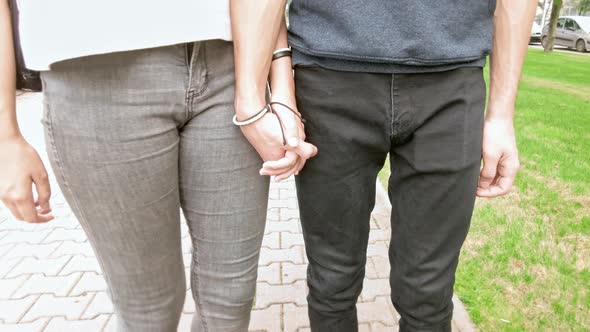 Girl and a Guy with Identical Bracelets are Walking Down the Street Holding Hands Camera Tracking