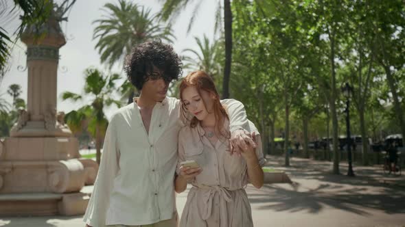 Romantic Couple Walking with Mobile Around City. Focused Couple Holding Hands