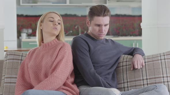 Sad Caucasian Man and Woman Sitting on Sofa, Girl Pushing Spouse with Shoulder, Upset Couple Having
